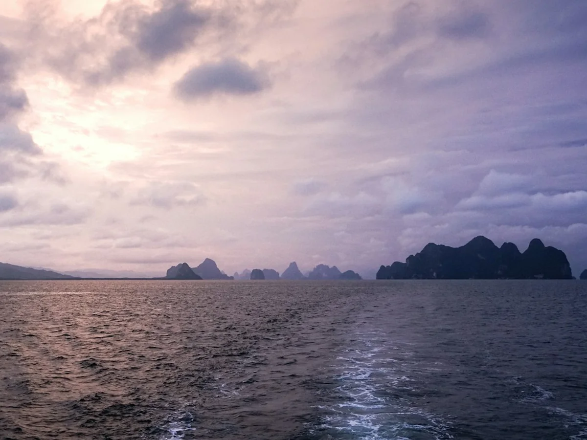 Siluety krasových ostrovů Phang Nga Bay za soumraku, typické pro večerní cestu zpět